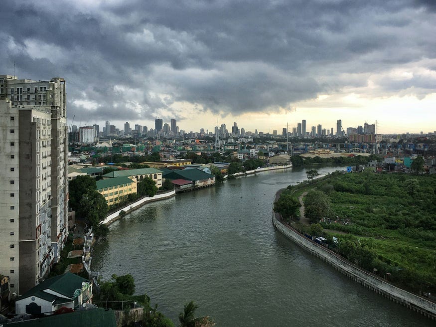 Lush green space alongside a flowing river. On the banks, a city rises into the horizon. High traffic could be improved with accessible public transportation.
