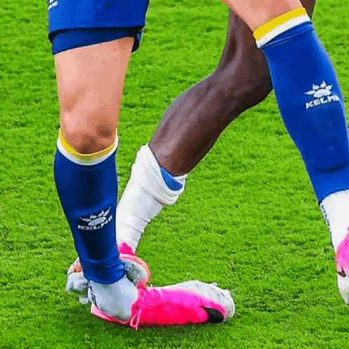 a soccer player wearing blue kelme socks kicks a pink soccer ball a soccer player wearing blue kelme socks kicks a pink soccer ball