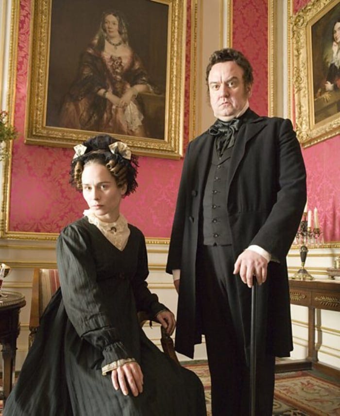 a stern woman in a black victorian dress with a frowning man in a black suit a stern woman in a black victorian dress with a frowning man in a black suit