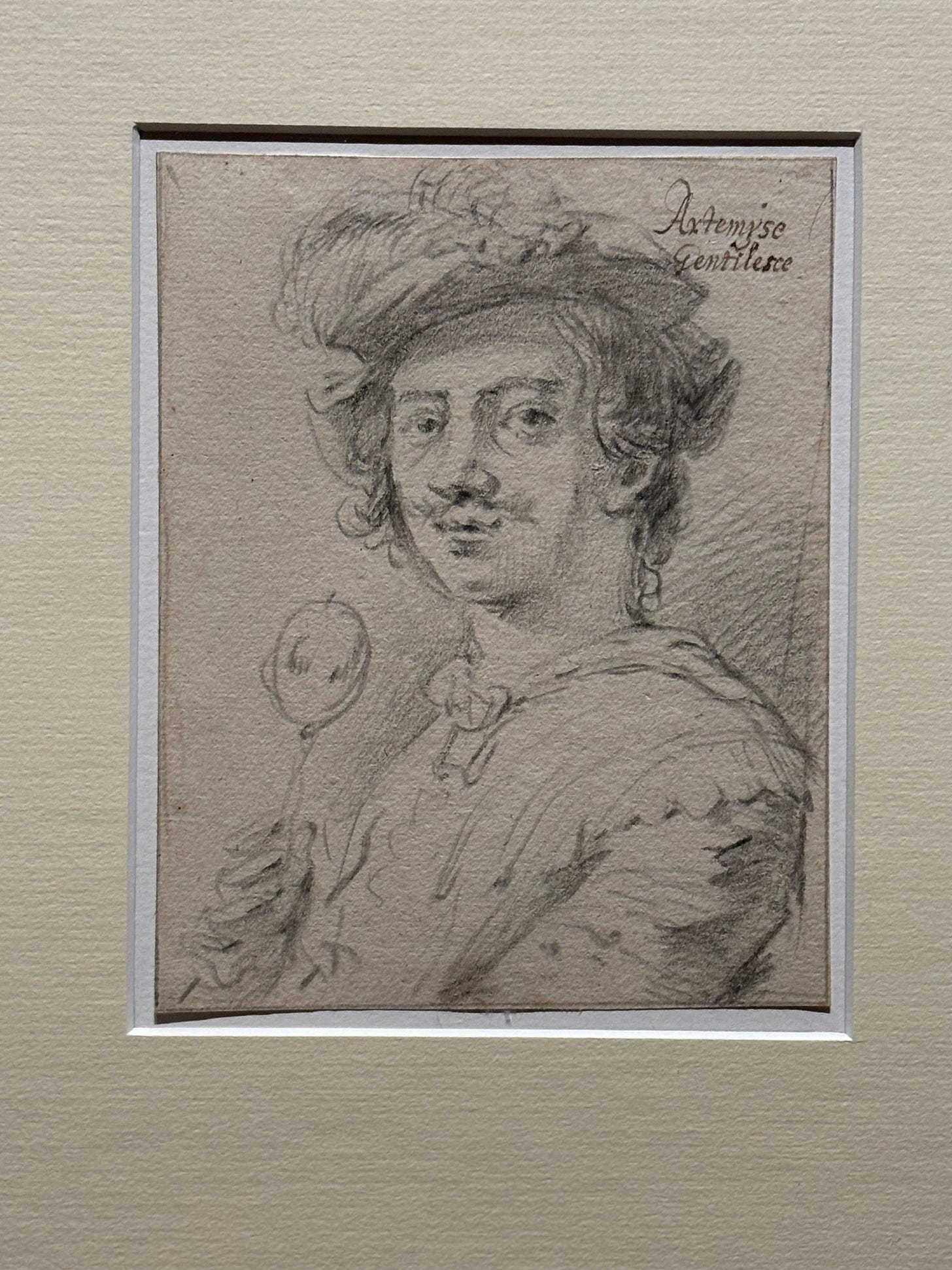 Sketch of Artemisia Gentileschi: Artemisia sits placidly, implacably in semi-profile, with a feathered cap, short unruly curls, and a spreading, breathy moustache, holding a candied apple. 