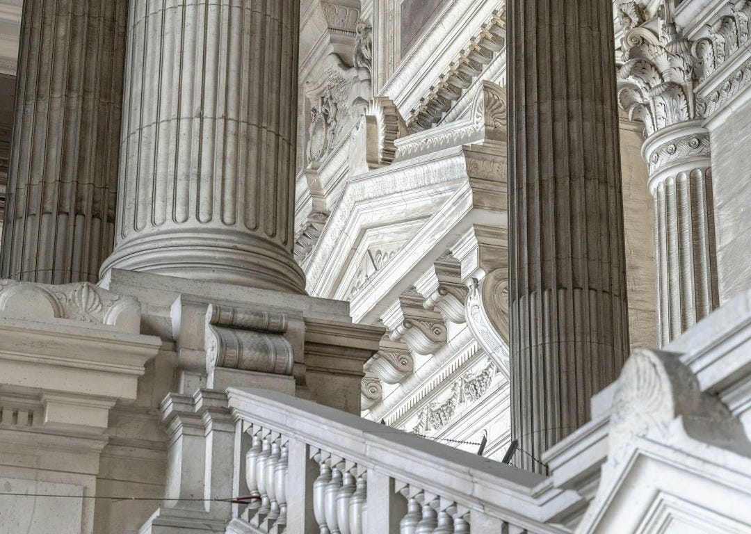 a building with columns and a clock on the side of it a building with columns and a clock on the side of it