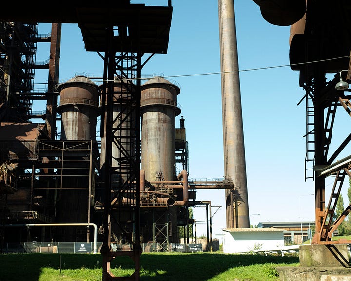 Colour photographs of decaying old steel factory; lots of rust pipes, stacks, and other industrial architecture