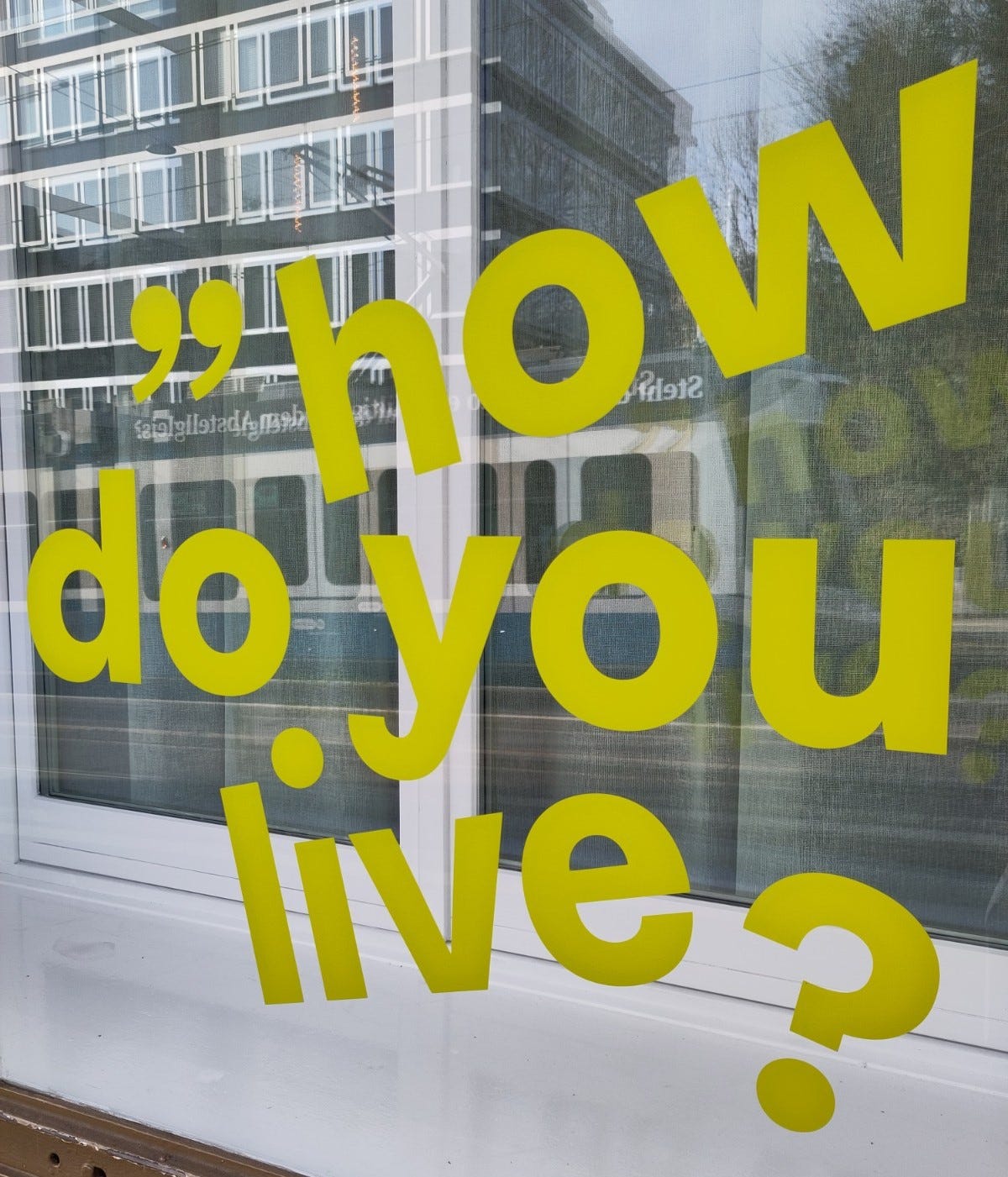 Vetrina su cui si legge la frase, scritta in lettere gialle, "how do you live?" Vetrina su cui si legge la frase, scritta in lettere gialle, "how do you live?"