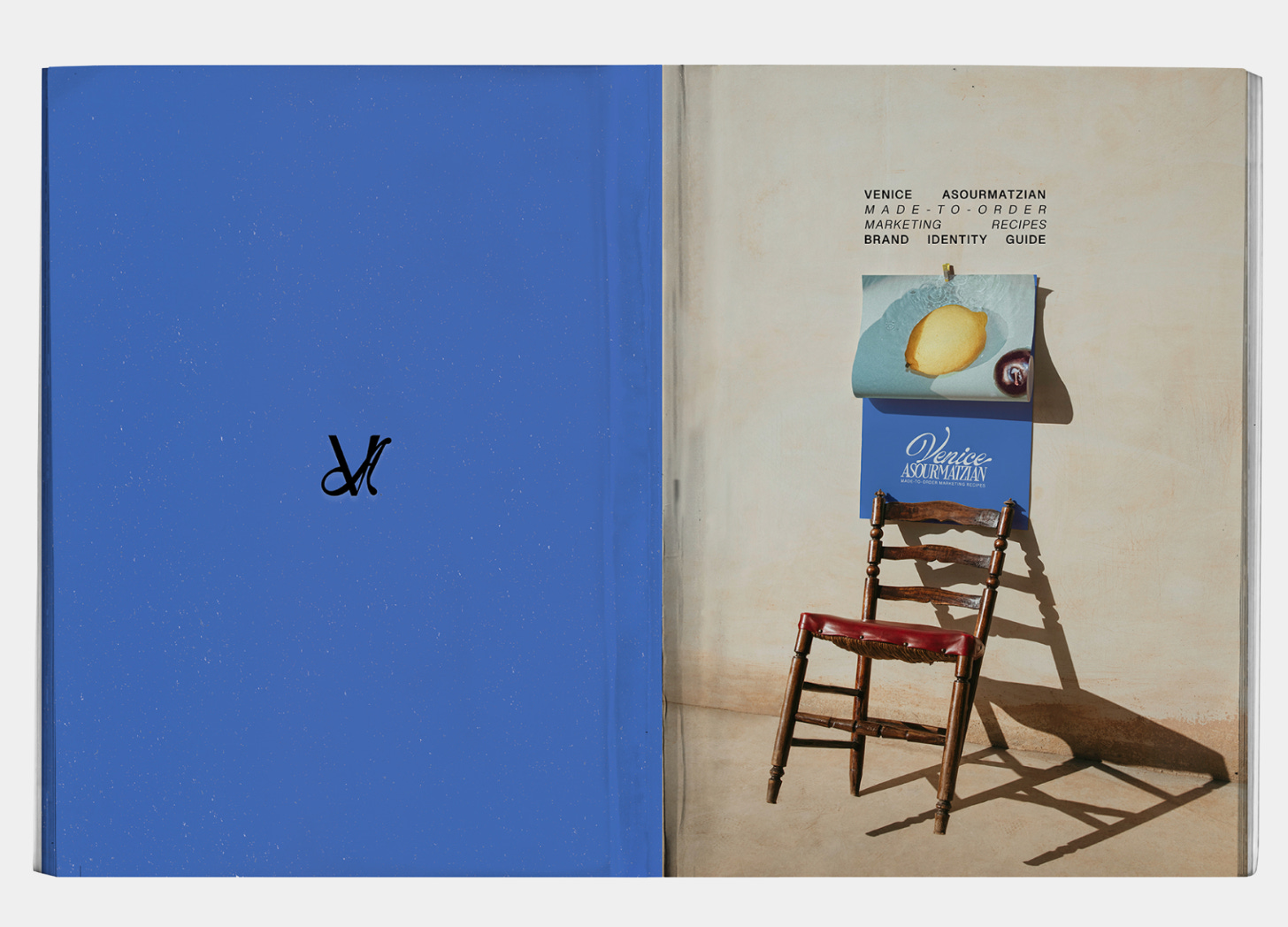 A stylised brand identity spread from Venice Asourmatzian’s “Marketing Recipes” guide. One side shows a bold cobalt blue cover with a minimalist ‘VA’ monogram; the other features a rustic wooden chair against a neutral wall, holding a calendar page with a lemon slice and a branded card pinned to it. A stylised brand identity spread from Venice Asourmatzian’s “Marketing Recipes” guide. One side shows a bold cobalt blue cover with a minimalist ‘VA’ monogram; the other features a rustic wooden chair against a neutral wall, holding a calendar page with a lemon slice and a branded card pinned to it.