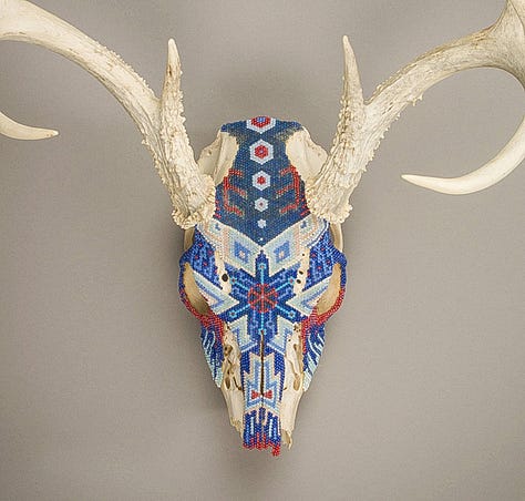 three deer skulls decorated with seed beads in geometric patterns