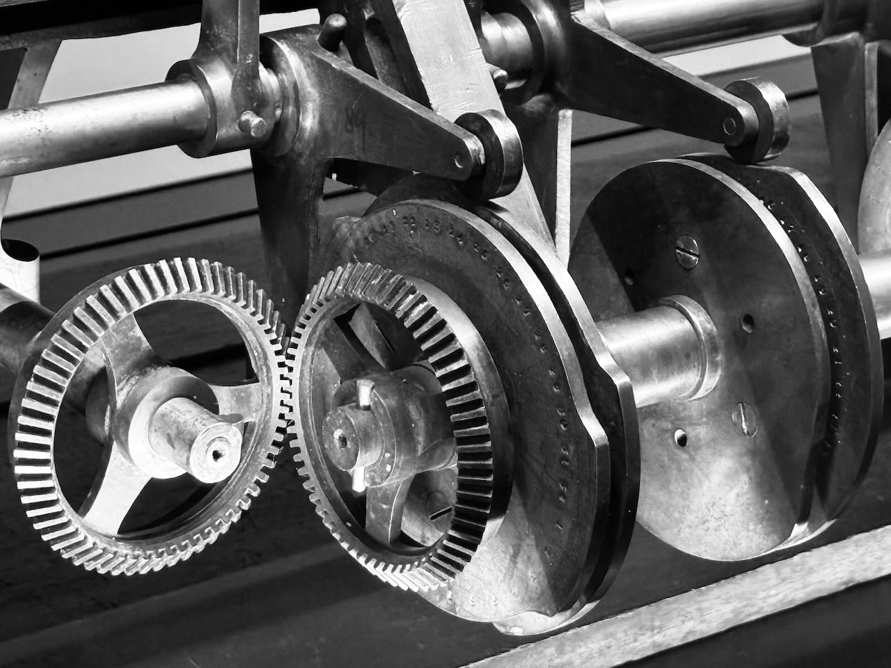 GPT-4o: This black-and-white photo showcases a close-up view of an intricate mechanical assembly, featuring several interlocking gears and rotating components. The gears are made of metal, with finely toothed edges that mesh together to transfer motion. The image highlights the precision engineering of the machinery, with various parts connected by rods and levers, suggesting an industrial or mechanical function. The play of light on the metal surfaces emphasizes the texture and craftsmanship of the gears, creating a visually striking and detailed composition. GPT-4o: This black-and-white photo showcases a close-up view of an intricate mechanical assembly, featuring several interlocking gears and rotating components. The gears are made of metal, with finely toothed edges that mesh together to transfer motion. The image highlights the precision engineering of the machinery, with various parts connected by rods and levers, suggesting an industrial or mechanical function. The play of light on the metal surfaces emphasizes the texture and craftsmanship of the gears, creating a visually striking and detailed composition.