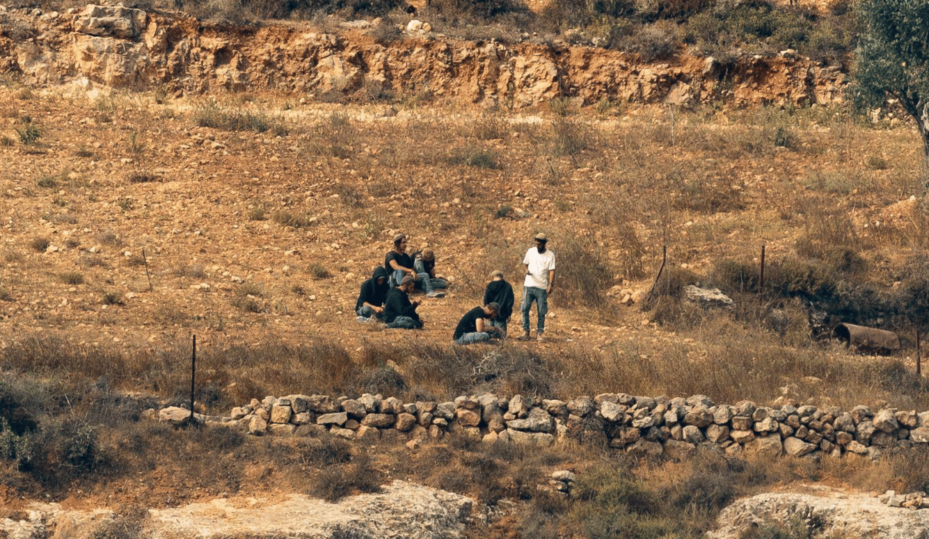 A group of people gather on a dry hillside above Qusra in the occupied West Bank.