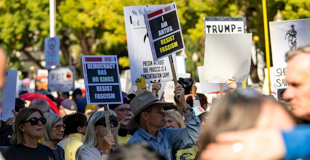 Protesters hold signs at a rally with trump banner Protesters hold signs at a rally with trump banner