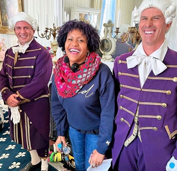 Hallmark Channel producer Tia A. Smith laughs alongside two men dressed in formal Regency suits, while Tia is in jeans and a jacket, holding props and equipment - the photos is from the set of the Hallmark Channel's film 'Sense and Sensibility' Hallmark Channel producer Tia A. Smith laughs alongside two men dressed in formal Regency suits, while Tia is in jeans and a jacket, holding props and equipment - the photos is from the set of the Hallmark Channel's film 'Sense and Sensibility'