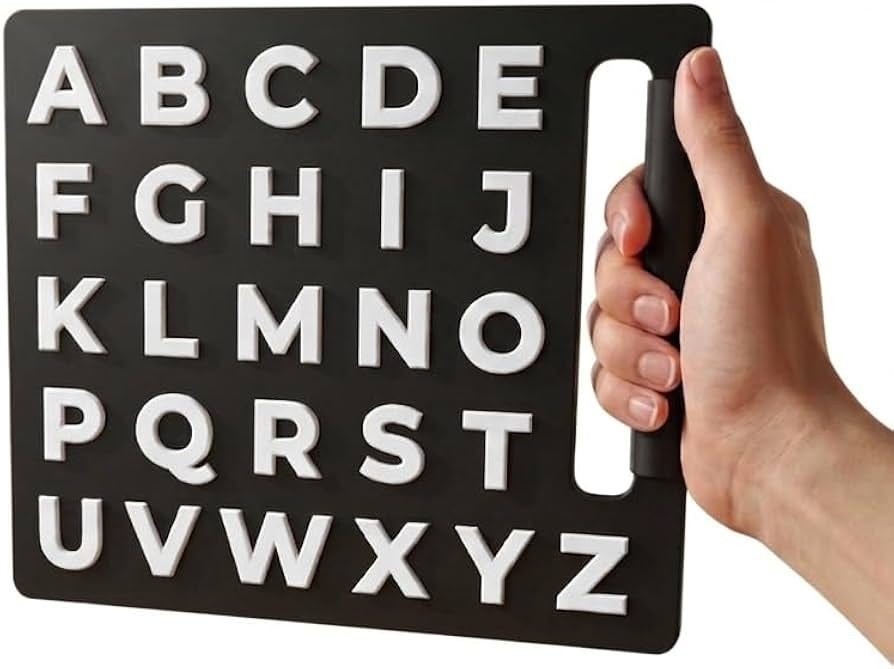 A hand holds a black letterboard with large white raised letters A through Z A hand holds a black letterboard with large white raised letters A through Z