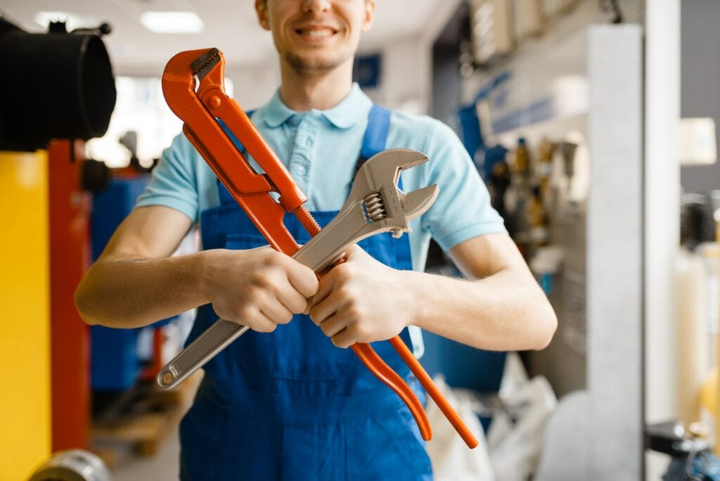 Plumber poses with pipe wrenches, plumbering store Plumber poses with pipe wrenches, plumbering store