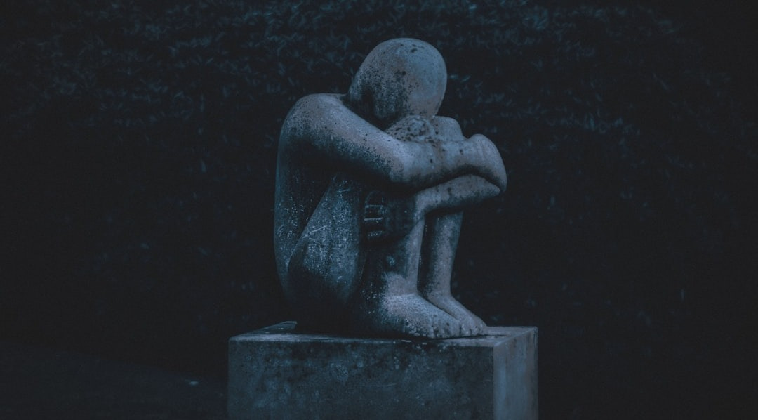man hugging his knee statue