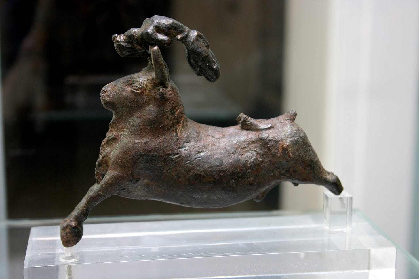 Bronze figurine of a galloping bull with a bull leaper arching over its horns, face upward. The leaper's lower arms and legs have broken off.