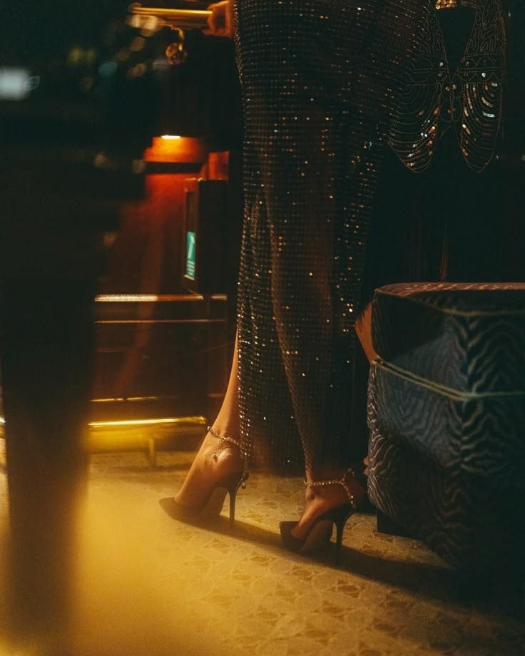 This may contain: a woman in high heels standing next to a table This may contain: a woman in high heels standing next to a table