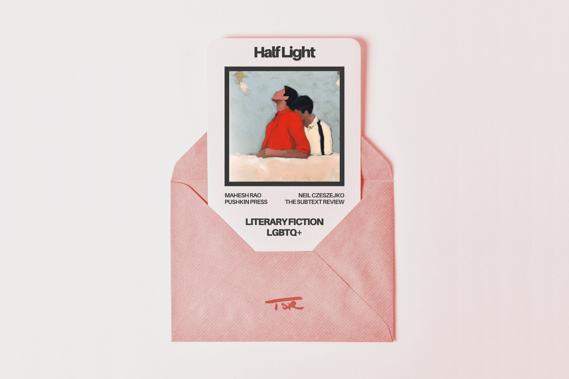A minimalist, flat-lay photograph of a soft pink envelope sitting on a pale background. Tucked inside the envelope is a textured card for the book "Half Light" by Mahesh Rao, published by Pushkin Press, and reviewed by Neil Czeszejko. The card showcases a square illustration, styled to look like a freshly printed photograph, depicting two Indian men, with one partner intimately embracing the other from behind under a pale blue sky. The genres "Literary Fiction | LGBTQ+" are printed on the card, and the envelope is stamped at the bottom with a red TSR logo. Part of the Literary Review series at The Subtext Review.