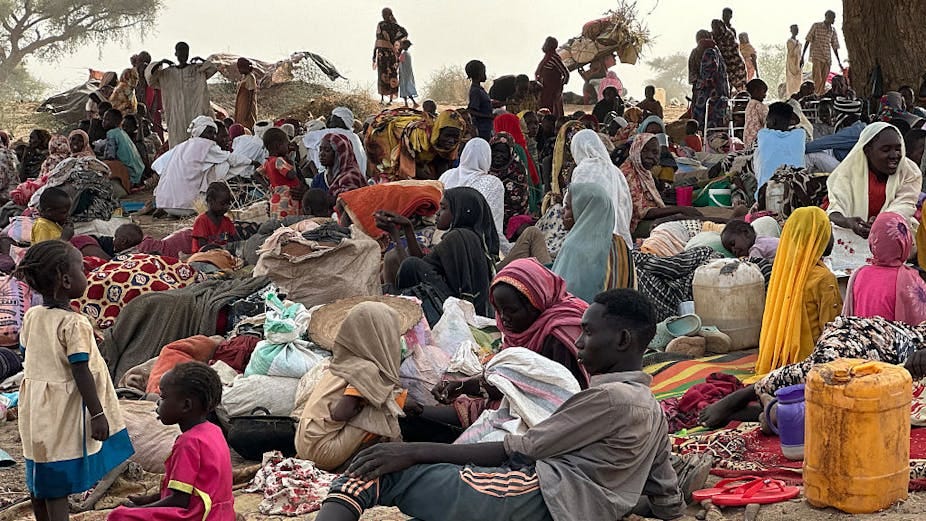 A group of men, women and children lying on the ground surrounded by bags and jerry cans. A group of men, women and children lying on the ground surrounded by bags and jerry cans.