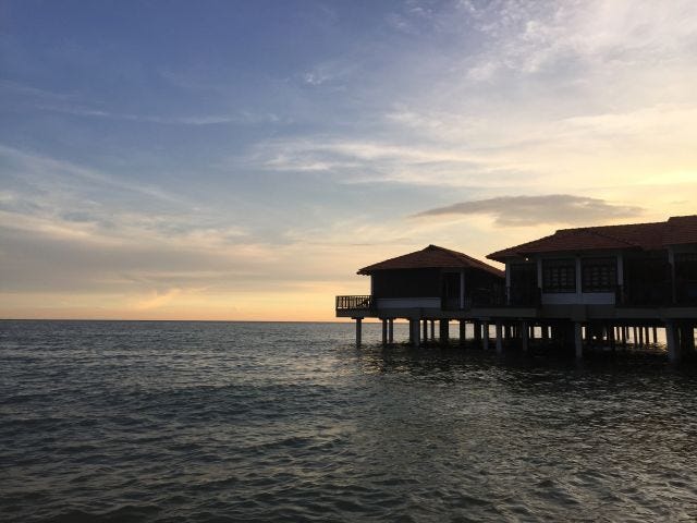 A sunset on waters with a series of beach houses on stints. A sunset on waters with a series of beach houses on stints.