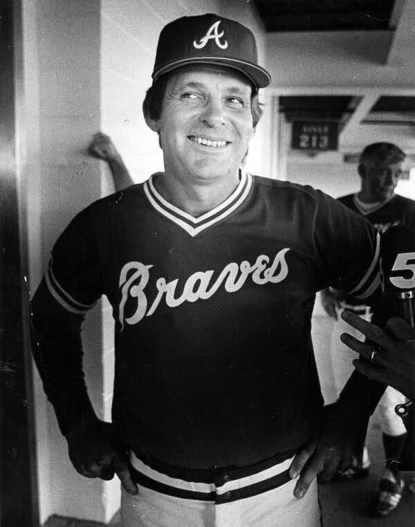 A black-and-white photo of a smiling man in an Atlanta Braves uniform.