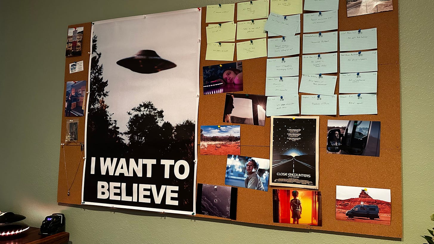 Large cork board with story notecards, UFO posters, and stills from a movie about UFOs