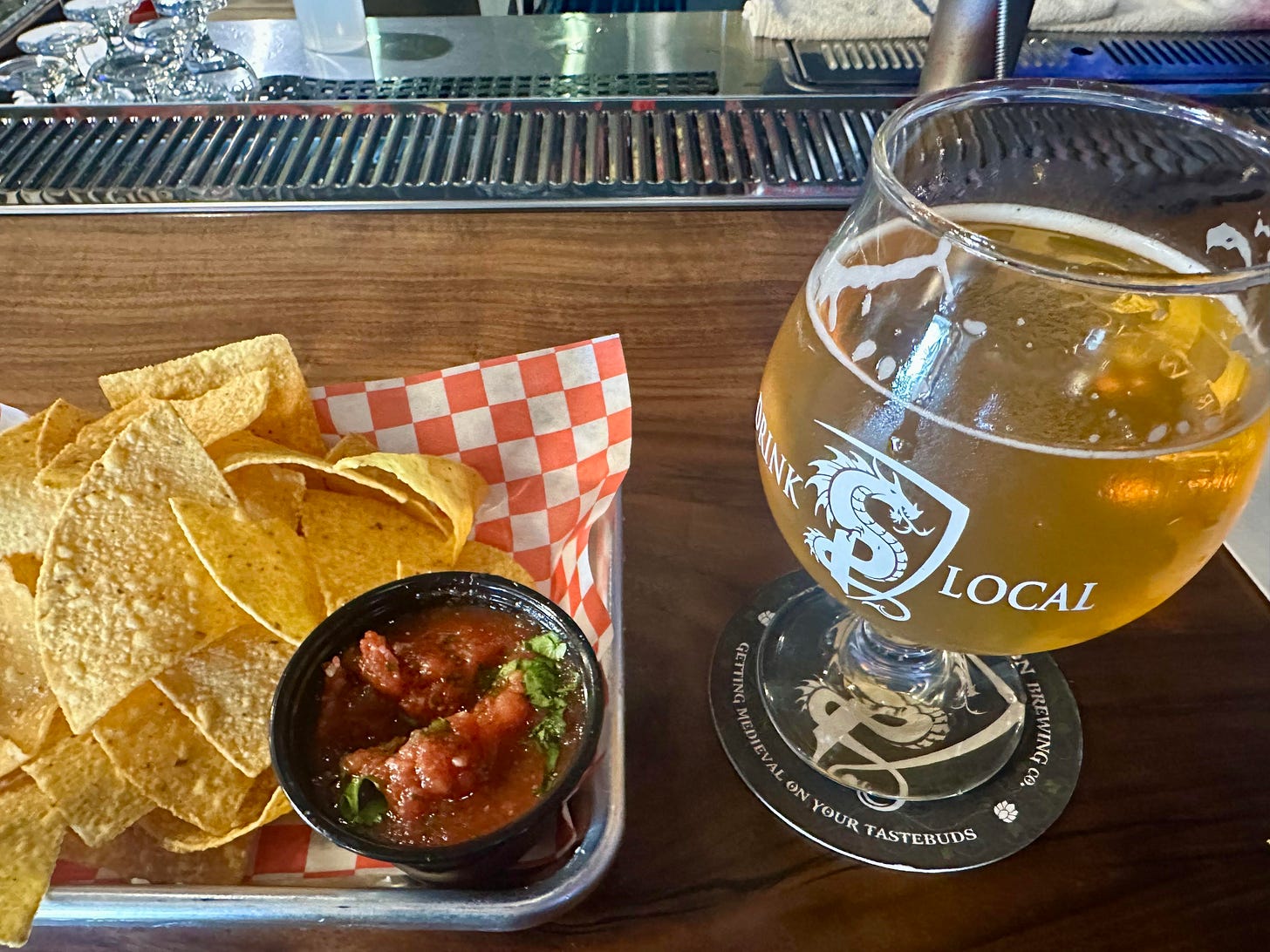 a basket of chips and salsa next to a tulip glass of west coast ipa