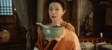 a woman in a traditional costume is holding a bowl of soup with a spoon in it .