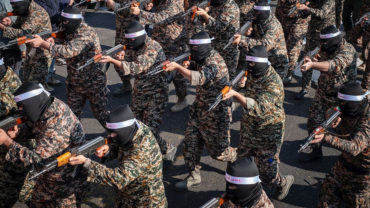 Islamic Revolutionary Guard Corps armed personnel wear masks and participate in a military rally.