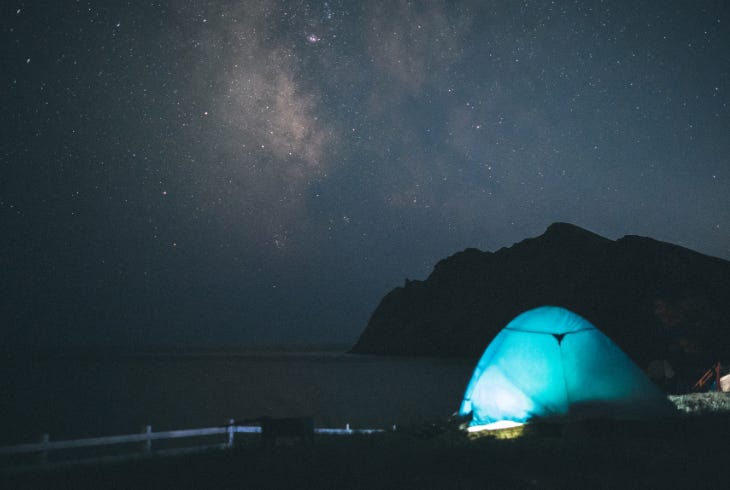 illuminated tent under a starry night sky