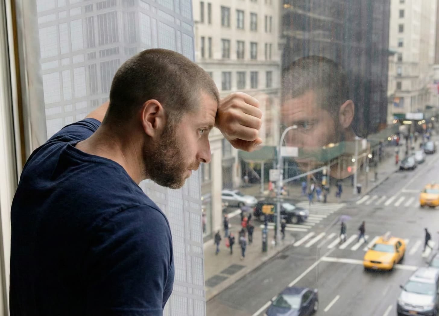 A man next to a window looking down at the people outside. A man next to a window looking down at the people outside.