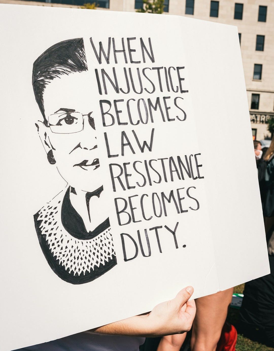 a person holding a sign that says when justice becomes law, resistance becomes duty