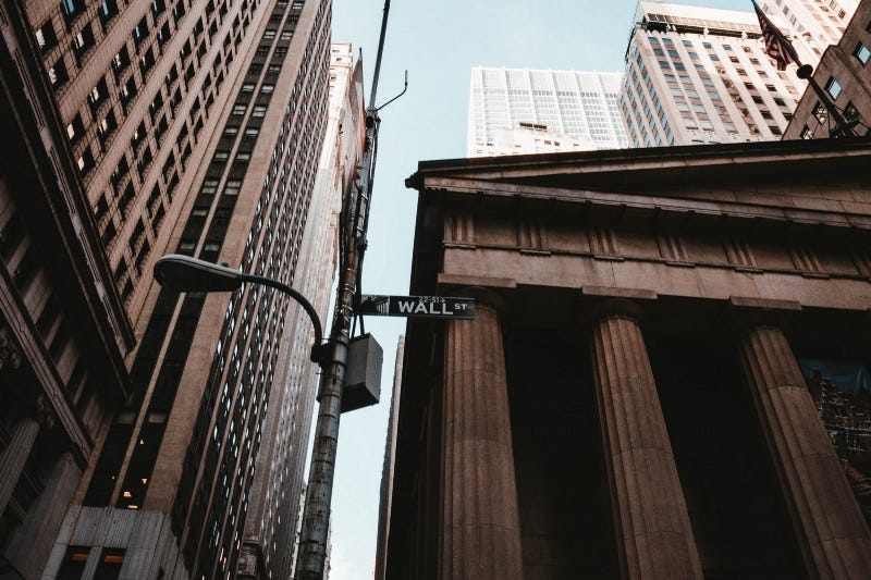A stone bank with a streetlight that reads “Wall Street” A stone bank with a streetlight that reads “Wall Street”