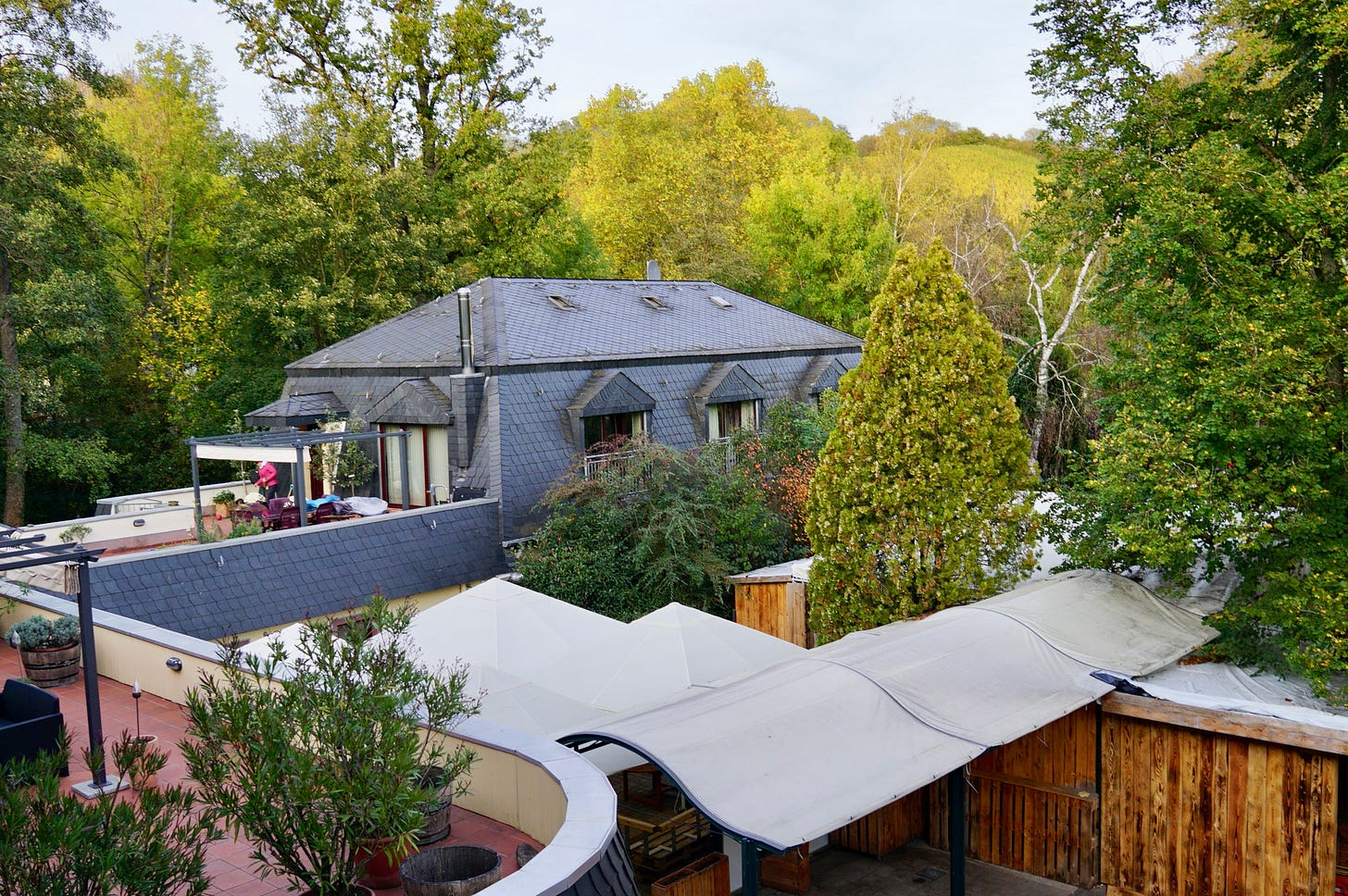 View across a roofed courtyard to part of a country hotel with vineyards behind