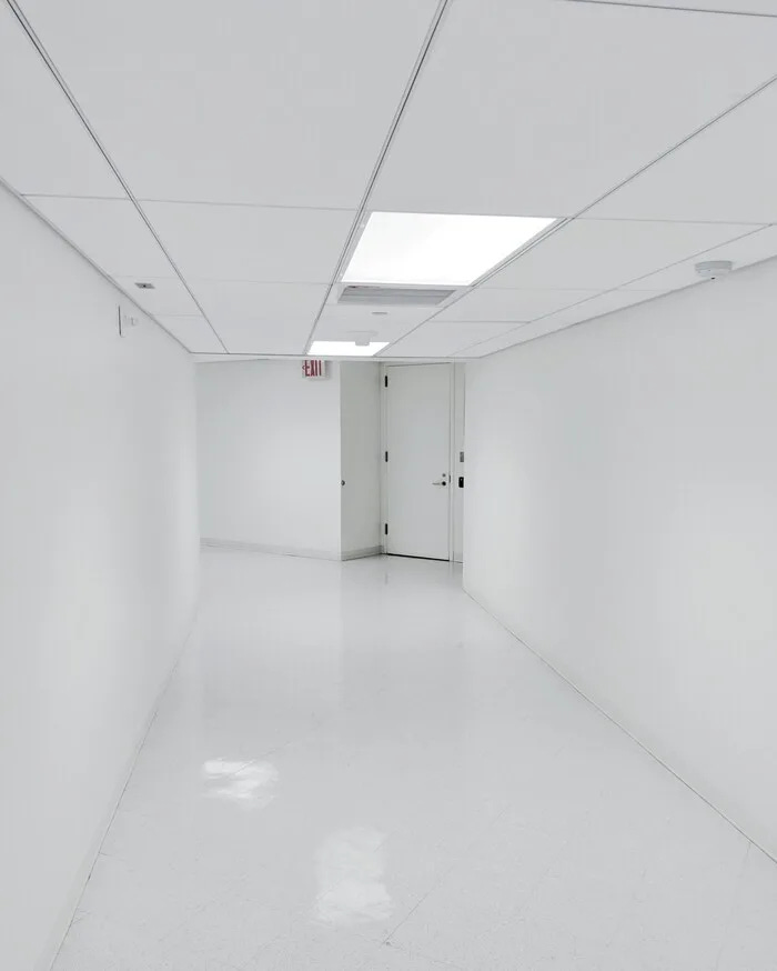 Fotografía de un pasillo iluminado por luz artificial blanca y sin ventanas