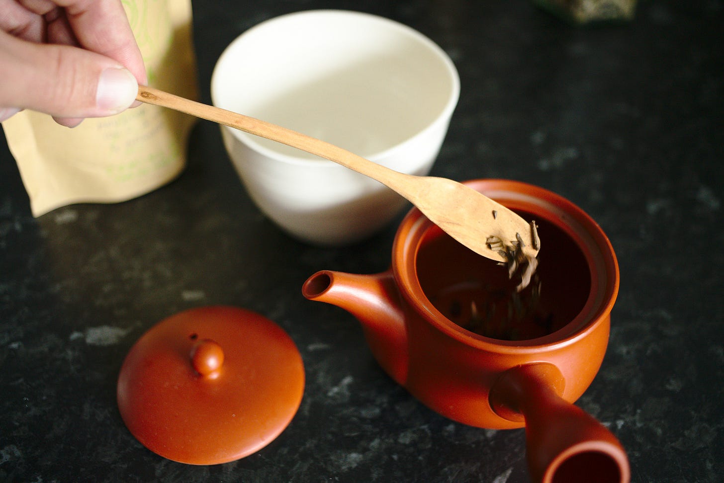 The same tea scoop, now dropping the tea into the pot.