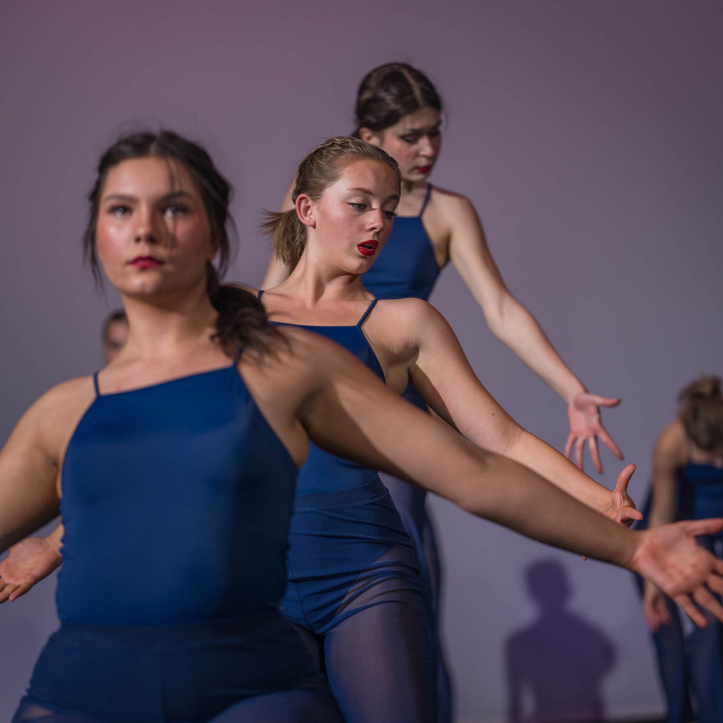 A group of senior dancers from NPA perform in perfect synchrony, dressed in navy blue leotards. The middle dancer, Aylen Bell, is in sharp focus, while Holly Elizabeth Thiele (front) and Julia Tybuszewska follow in formation, their movements fluid and expressive. The image conveys the beauty, discipline, and artistry of their performance. A group of senior dancers from NPA perform in perfect synchrony, dressed in navy blue leotards. The middle dancer, Aylen Bell, is in sharp focus, while Holly Elizabeth Thiele (front) and Julia Tybuszewska follow in formation, their movements fluid and expressive. The image conveys the beauty, discipline, and artistry of their performance.