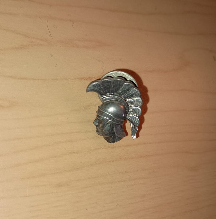 a pewter trojan warrior head side view and a white button with red words I love you
