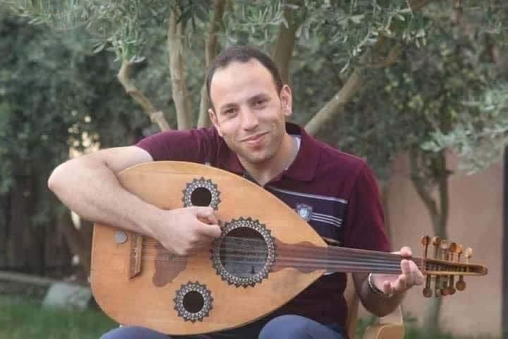 A person sitting on a chair playing a lute

Description automatically generated