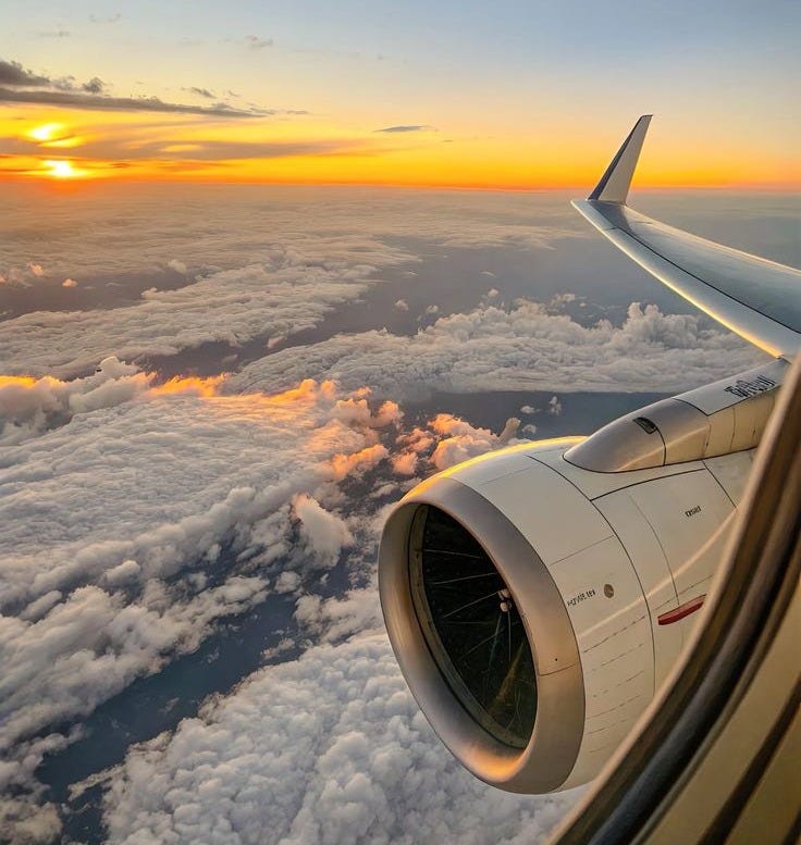 This may contain: the wing of an airplane as it flies through the clouds at sunset or sunrise over water