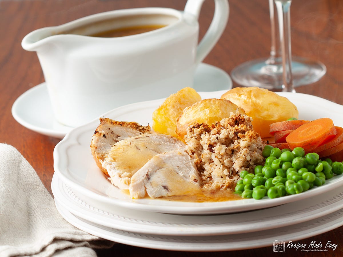 Serving of roast chicken with vegeatbles garvy jug behind.