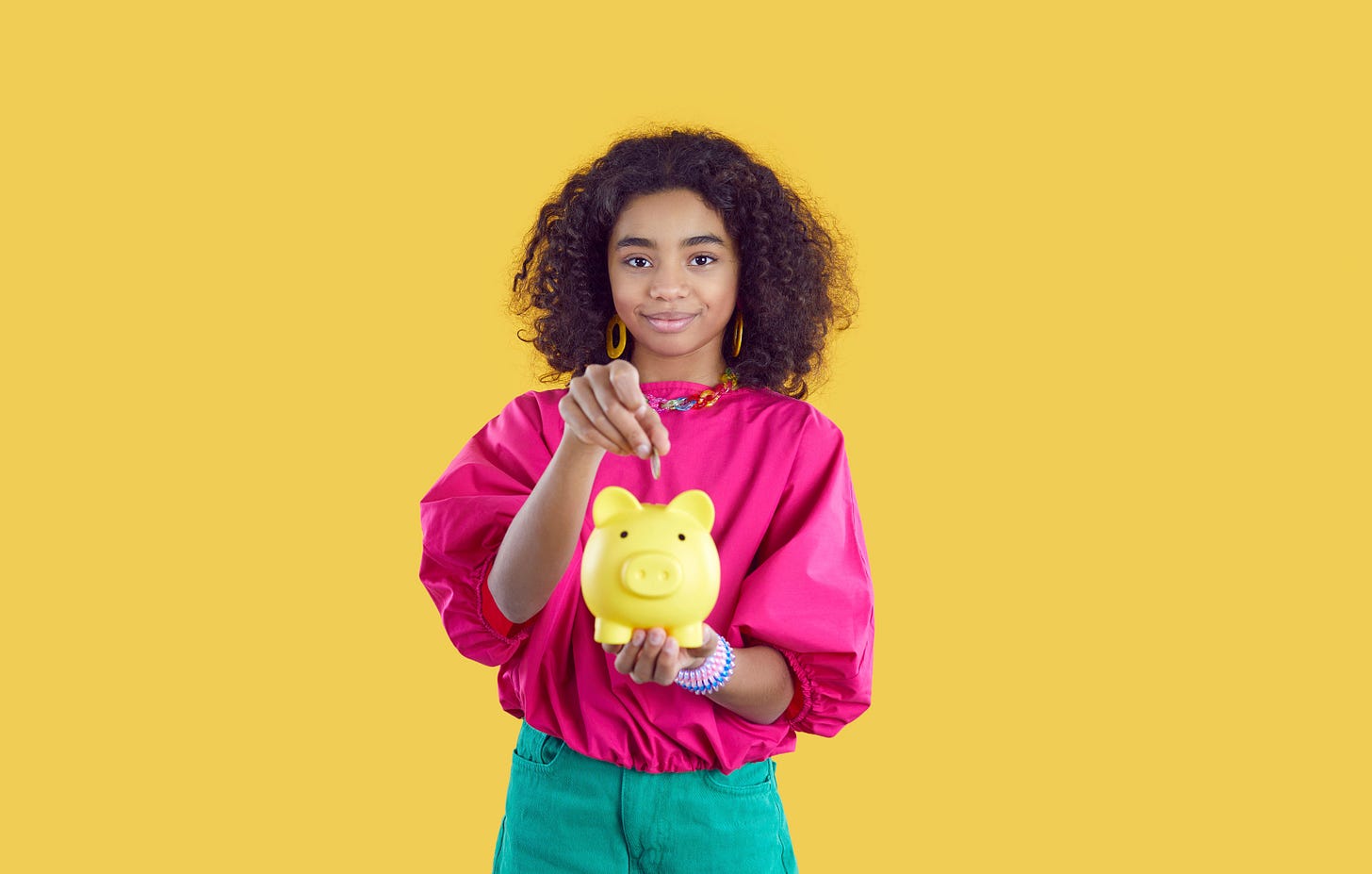 Young girl putting money in a piggy bank