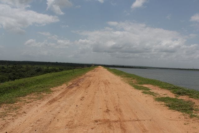 A long muddy road with grass on one side and waters on the other side A long muddy road with grass on one side and waters on the other side