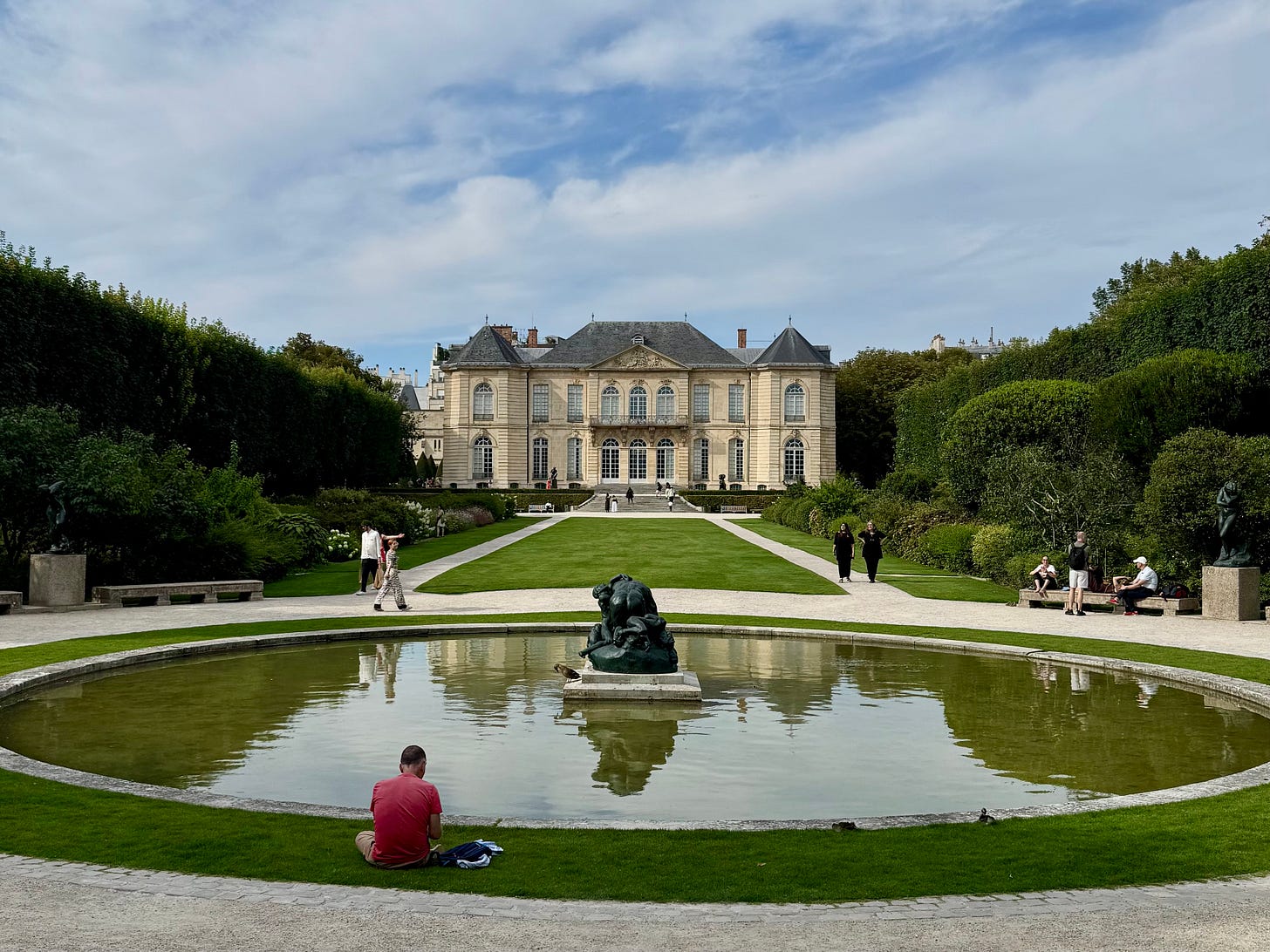 A photograph of a European mansion and its grounds, with a fountain in front that has a bronze sculpture in the middle. Grounds of the Museé Rodin in Paris A photograph of a European mansion and its grounds, with a fountain in front that has a bronze sculpture in the middle. Grounds of the Museé Rodin in Paris