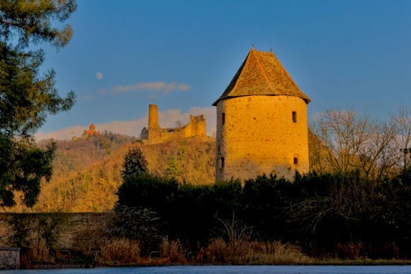 A stone tower with a castle in the background