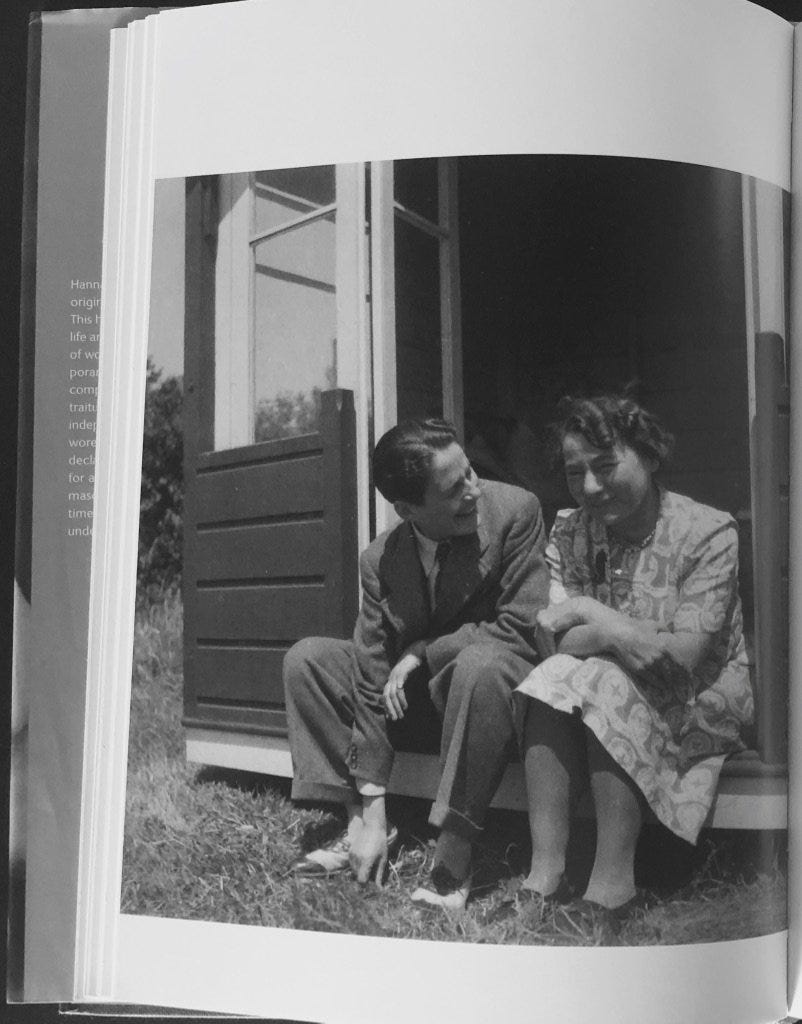 Black and white photo of Gluck in a suit and a woman in a patterned dress sitting on a porch step, smiling and engaging in conversation. This is an image taken from a book, with the photo on the left side of a page. Gluck is sitting on the left, touching the grass, and looking over at Edith and smiling. Edith is looking downward, with her arms crossed, mid-conversation. Gluck is wearing a suit and dapper shoes, with their short hair. Edith has short curly hair, and is wearing a dress and small heels. Black and white photo of Gluck in a suit and a woman in a patterned dress sitting on a porch step, smiling and engaging in conversation. This is an image taken from a book, with the photo on the left side of a page. Gluck is sitting on the left, touching the grass, and looking over at Edith and smiling. Edith is looking downward, with her arms crossed, mid-conversation. Gluck is wearing a suit and dapper shoes, with their short hair. Edith has short curly hair, and is wearing a dress and small heels.