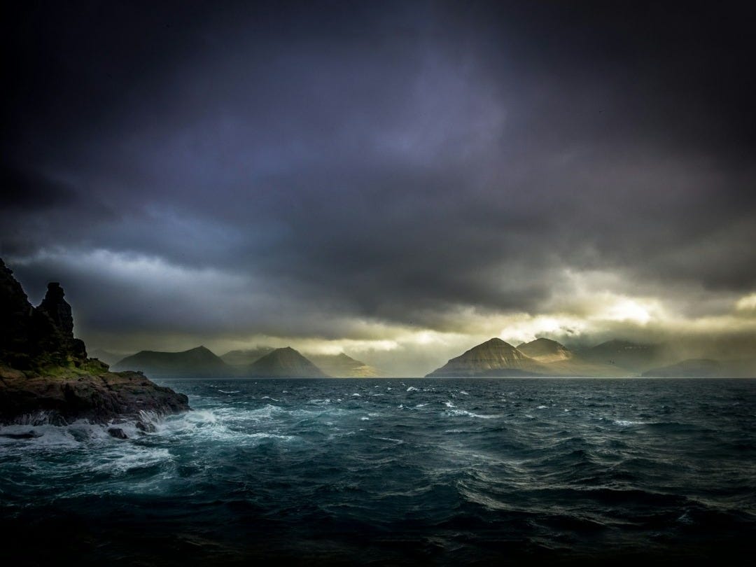 landscape photo of waters, mountains, and black clouds landscape photo of waters, mountains, and black clouds