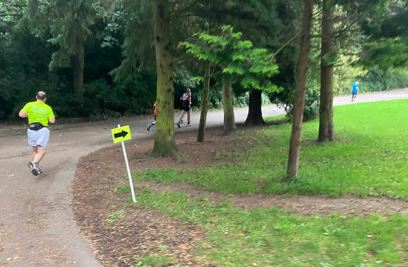 A sign points participants right, to head uphill on a tarmac path