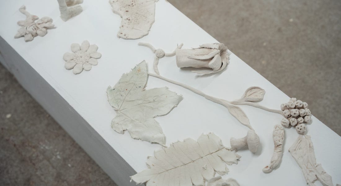 A white table with clay leaves and flowers on it A white table with clay leaves and flowers on it