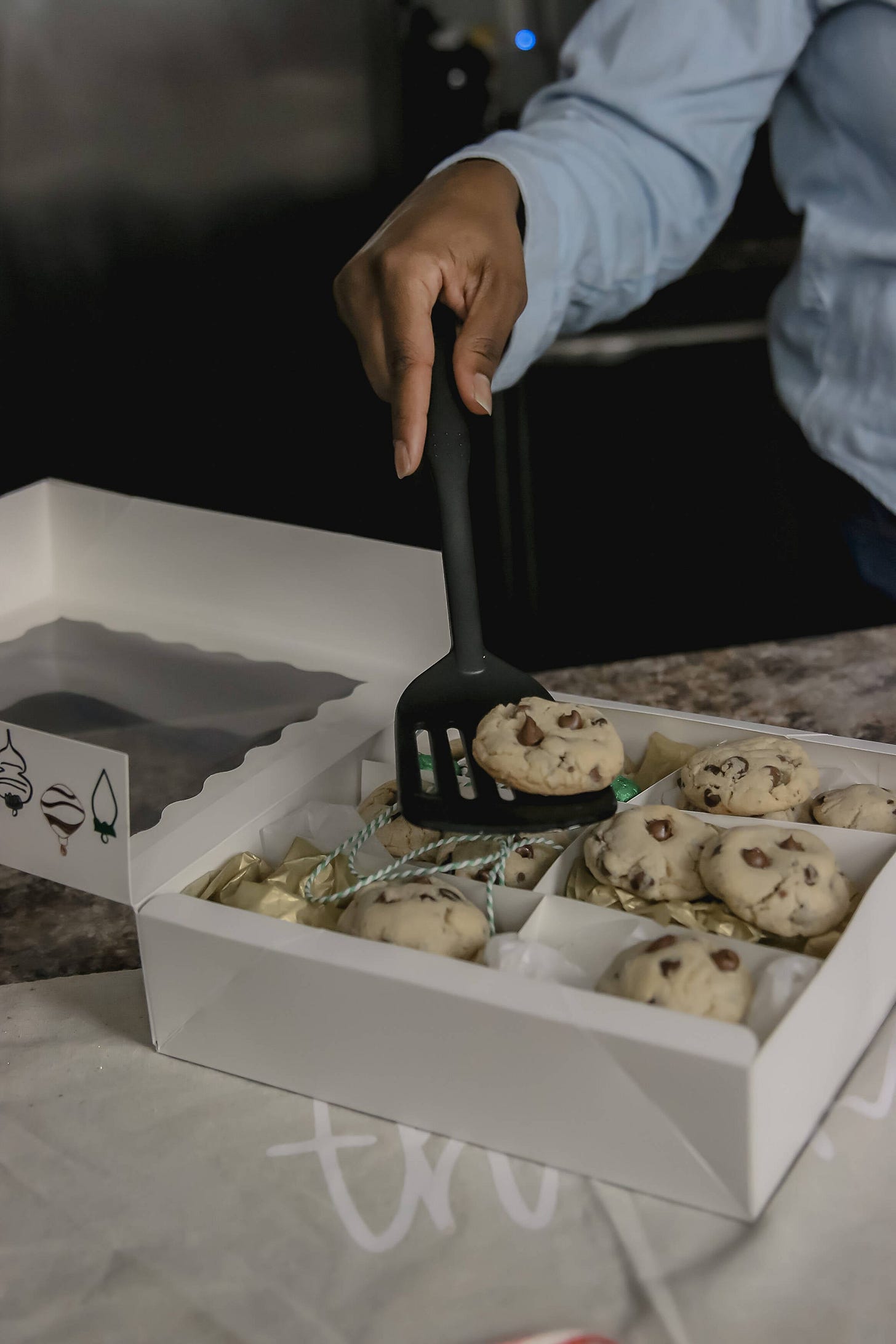 a black spatula lifting a cooked out of a box of chocolate chip cookies 