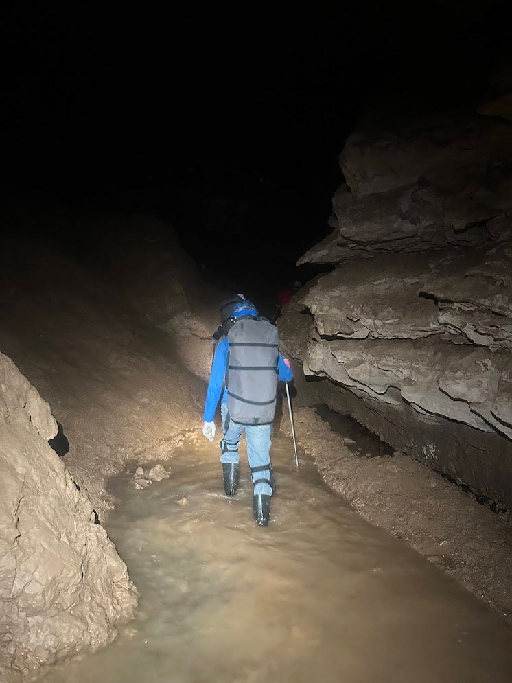 A caver walking in water with a ski pole for support A caver walking in water with a ski pole for support