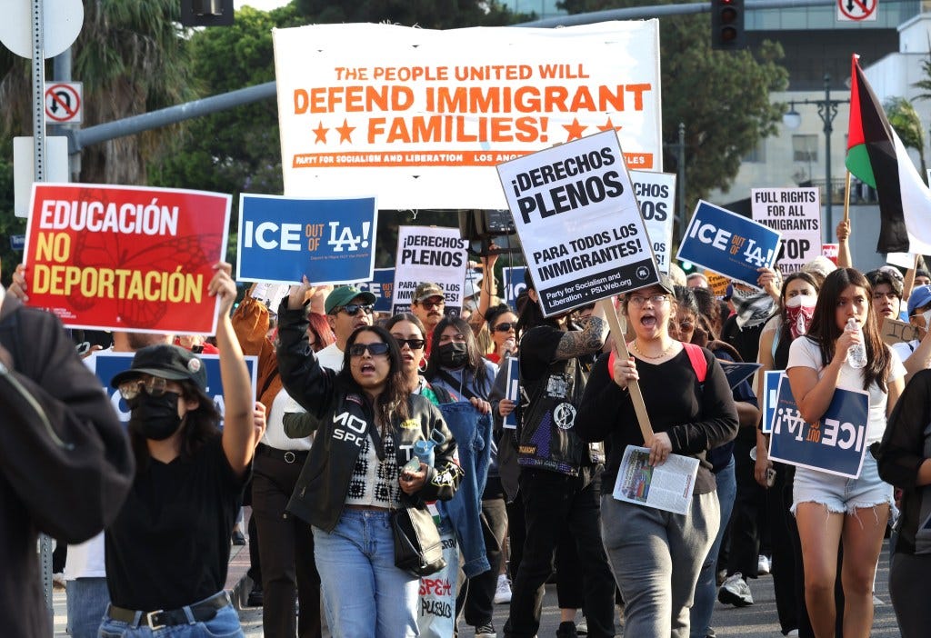 Protestors march with signs advocating for immigrant families.