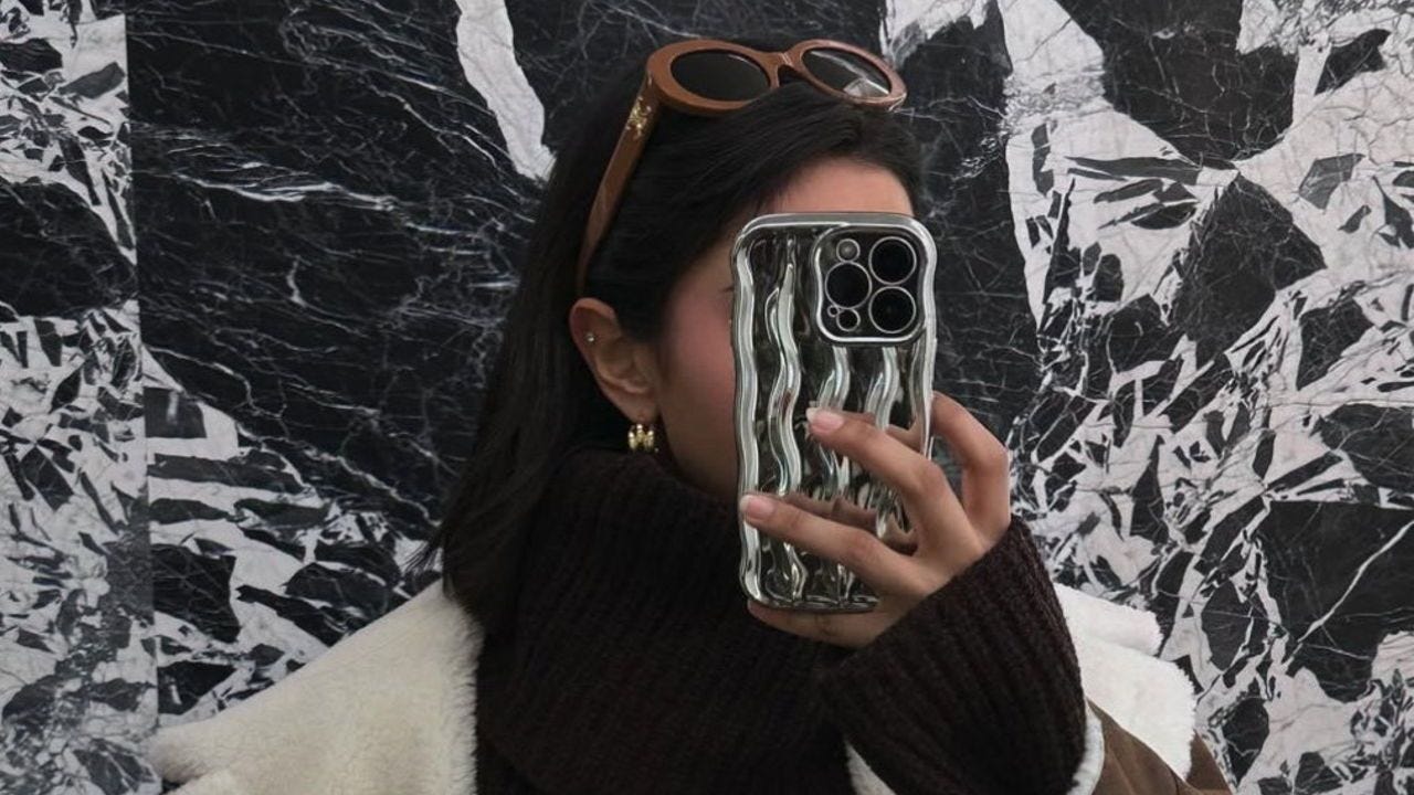 A picture from hamda.kb's Instagram. 'Faceless Influencer' takes selfie with phont in front of face, black and white patterns on smartphone and wall in background.